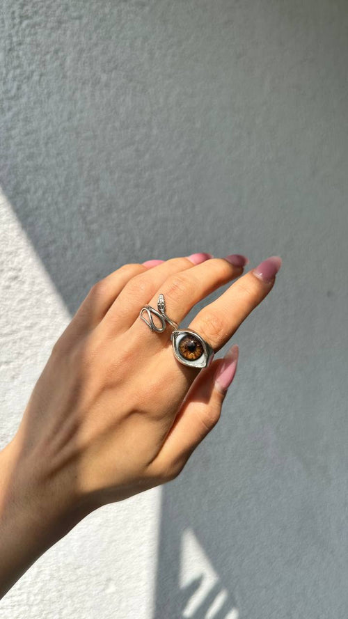 Silver almond eye ring with an amber hand-painted iris, worn in sunlight